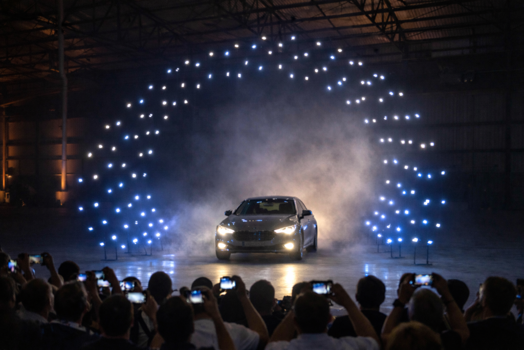 Car unveiling with dramatic indoor drone show lighting effects