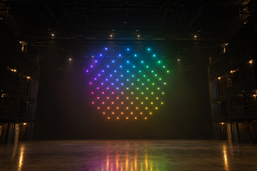 Dome-shaped light-painting drone formation above an empty theatre stage
